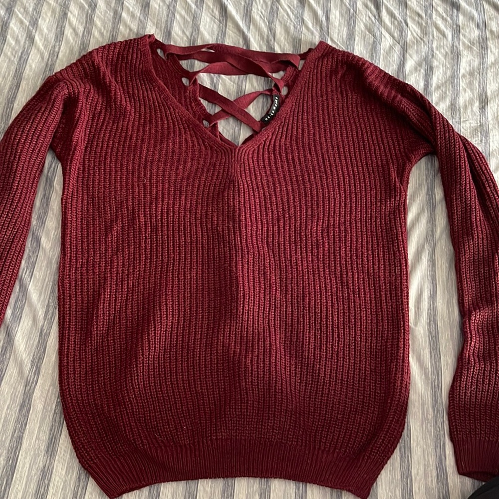 Burgundy sweater with crisscross ribbon in back.